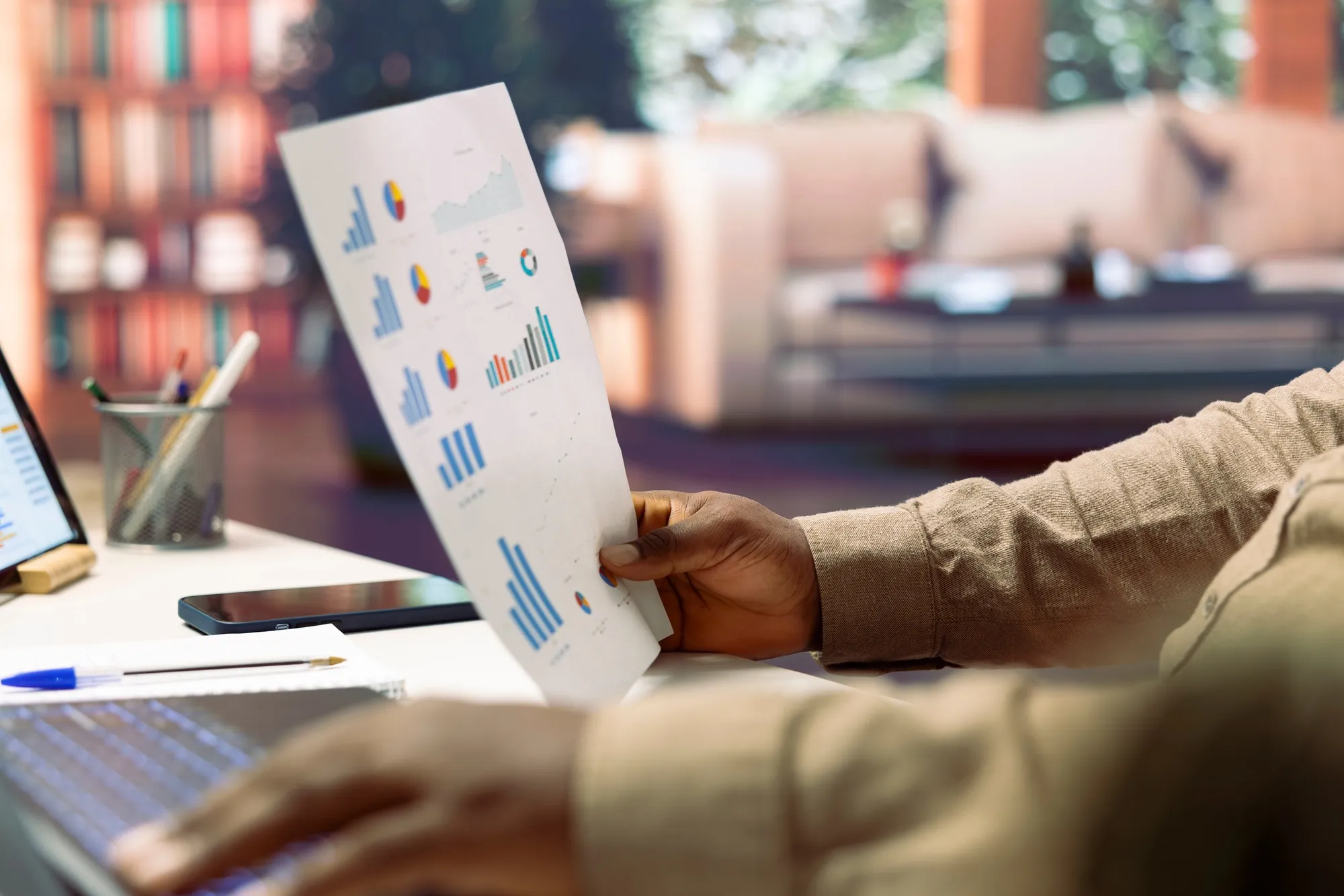Business owner reviewing data infographics on papers at his home office setup